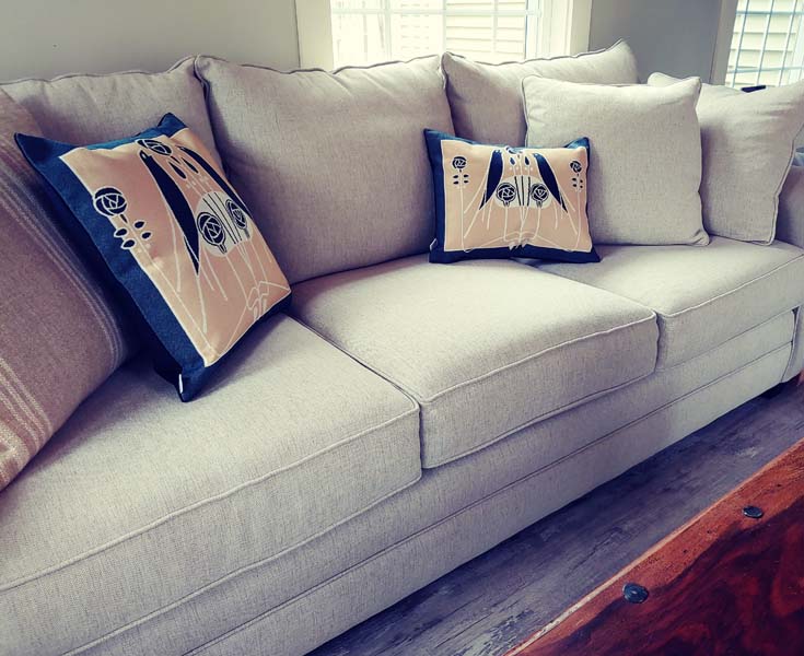 Birds of a Feather pillows styled on sofa with neutral décor, showing art-glass inspired woven details